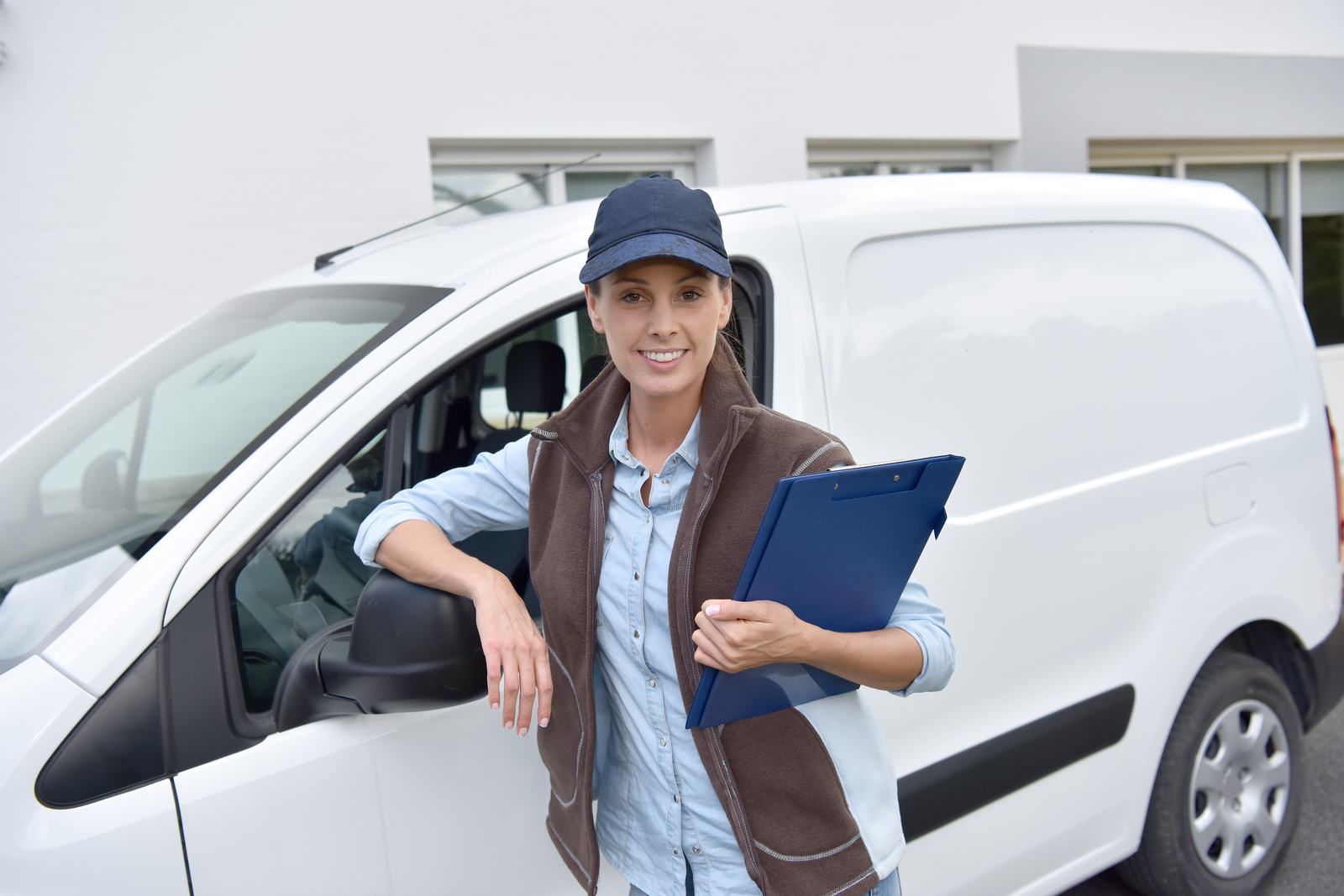 A courier with a clipboard next to her van