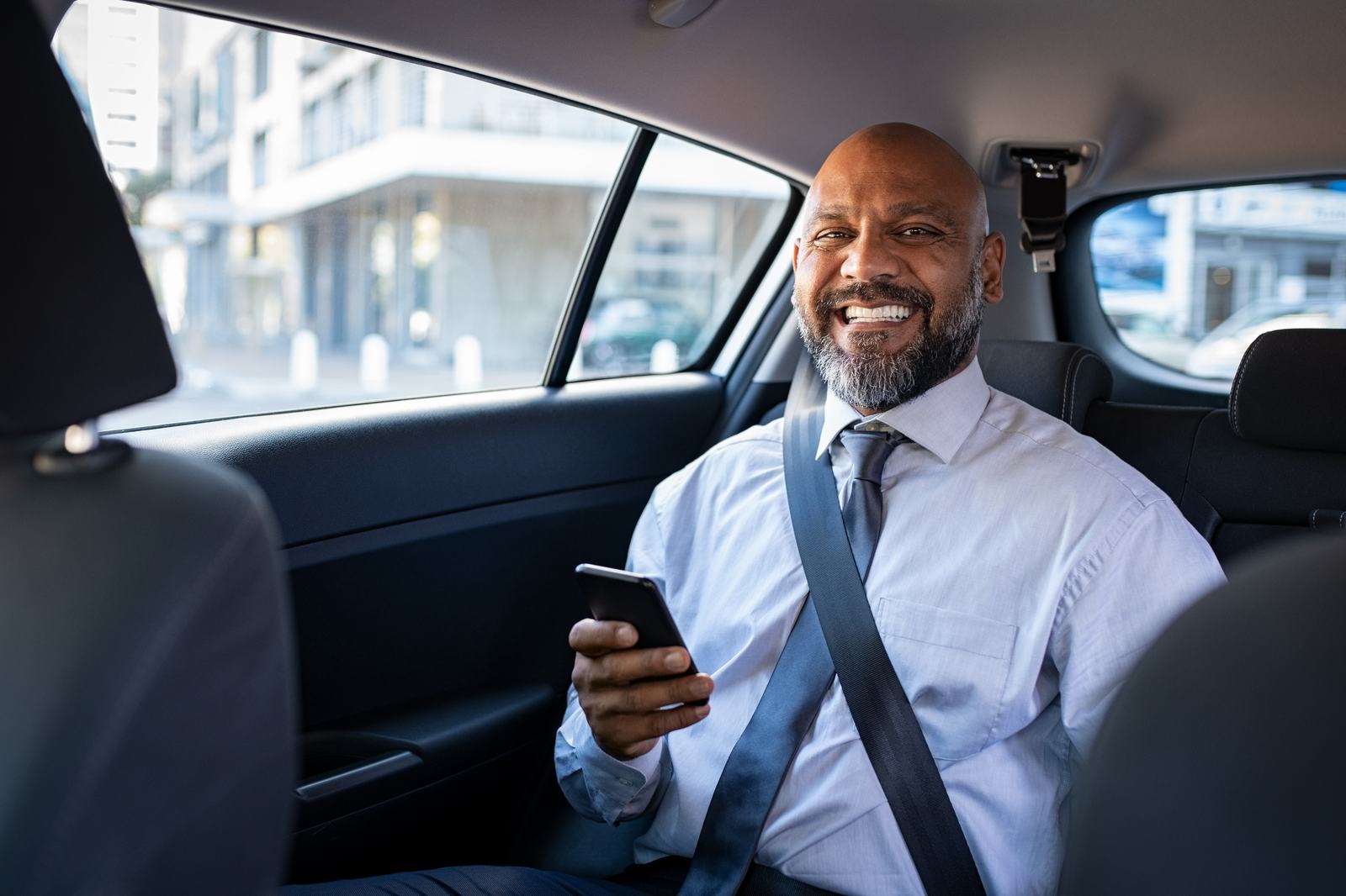 A passenger checking his phone in the back seat